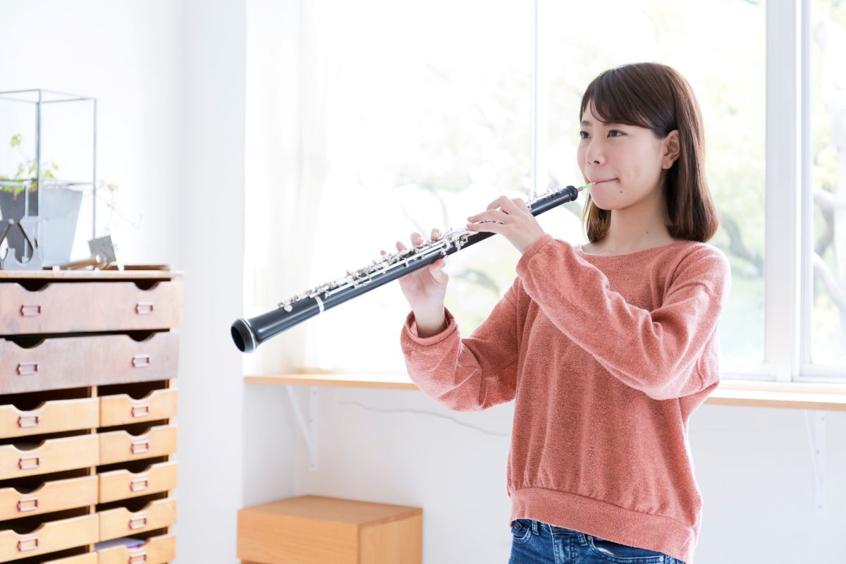 A female teenager playing the oboe at home
